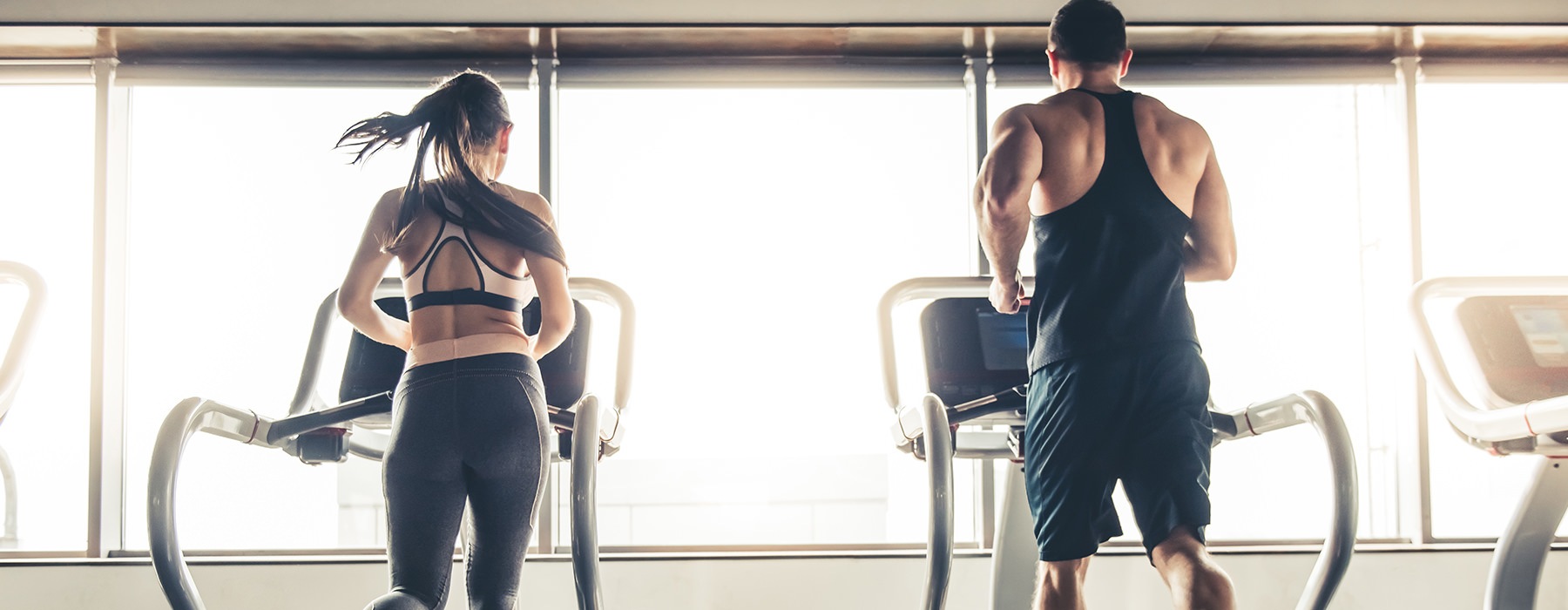 couple running on treadmills in fitness center