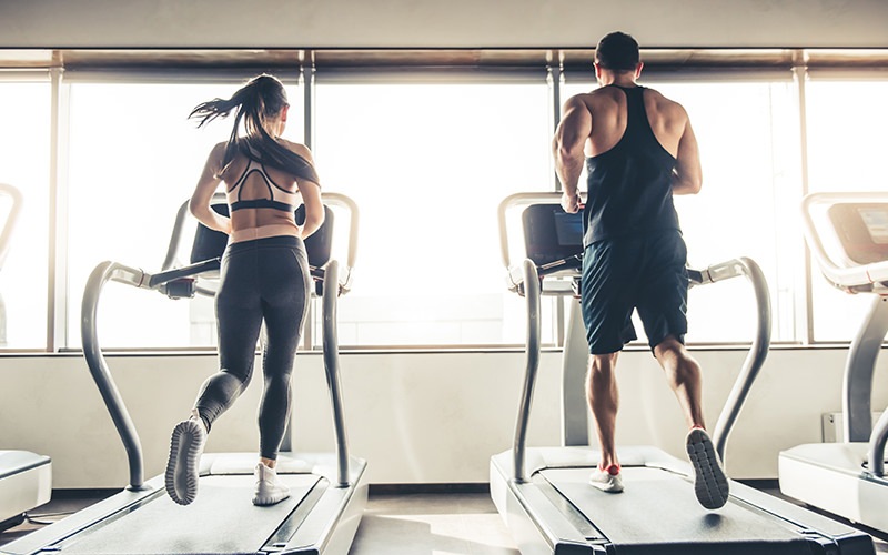 couple running on treadmills in fitness center